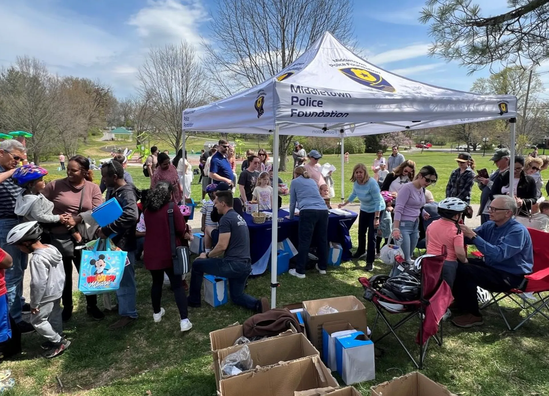 Volunteers fit children with bike helmets at police foundation tent.